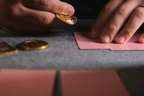 Hand placing bitcoin token on playing cards table Stock Photos