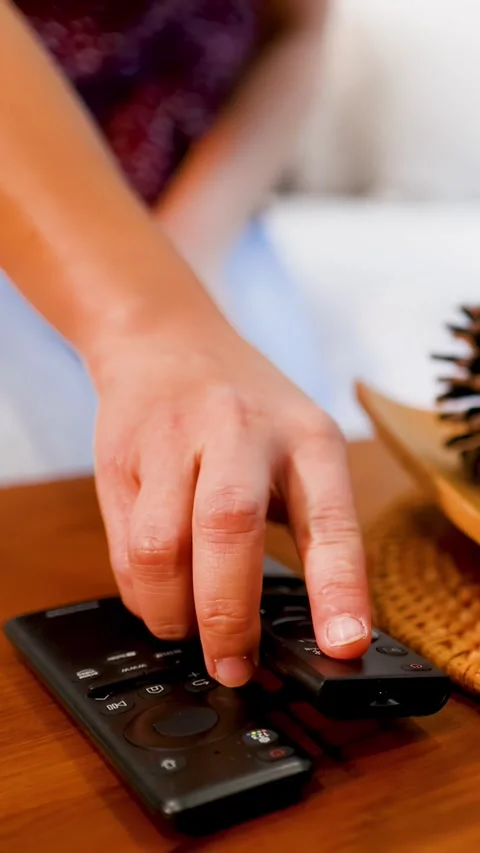 Hand Placing a Black Remote Control on a Wooden Coffee Table Stock Footage 333164902
