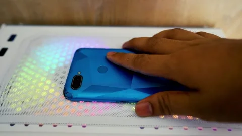Hand placing a blue geometric-patterned smartphone on a colorful illuminate.. Stock Footage 315981327
