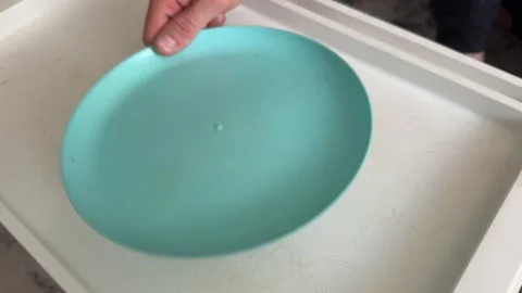 Hand placing blue plastic plate in kitchen sink Stock Footage 336976522