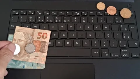 Hand placing brazilian money notes on laptop keyboard motion footage 動画素材 339091192