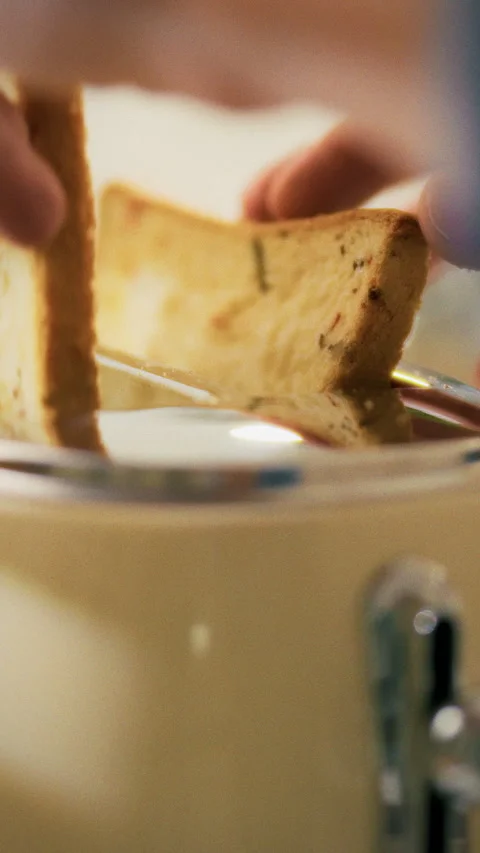 Hand placing bread in toaster during morning toast preparation in kitchen Stock Footage 331595139