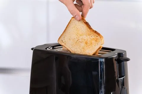 Hand placing bread into toaster, inserting and preparing slice for toasting,  Stock Photos