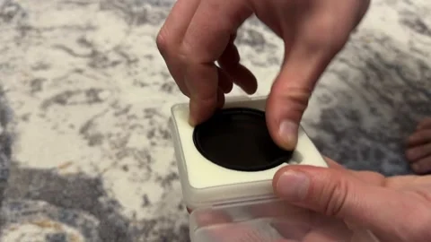 Hand placing camera lens cap onto small charging dock or device stand, Stock Footage 337121222