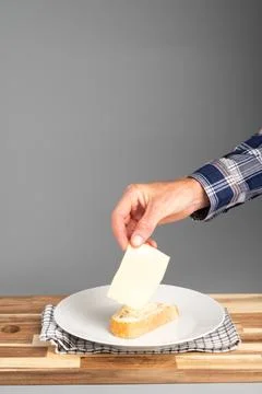 Hand Placing Cheese on Bread Slice Stock Photos