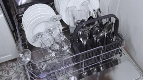 Hand placing clean glassware and utensils into a dishwasher rack filled with Stock Footage 324294794