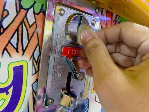 A Hand Placing a Coin into a Game Machine Stock Photos