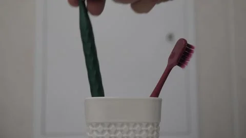 Hand placing colored toothbrushes in cup Stock Footage 342865090