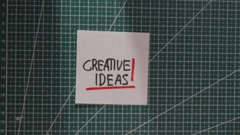 Hand placing Creative Ideas handwritten paper note on grid mat Stock Footage 341269367