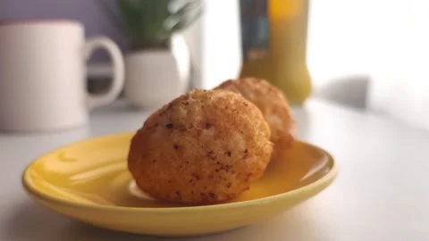 Hand placing crispy fried boiled eggs one by one onto a yellow saucer Vídeos de archivo 334700544