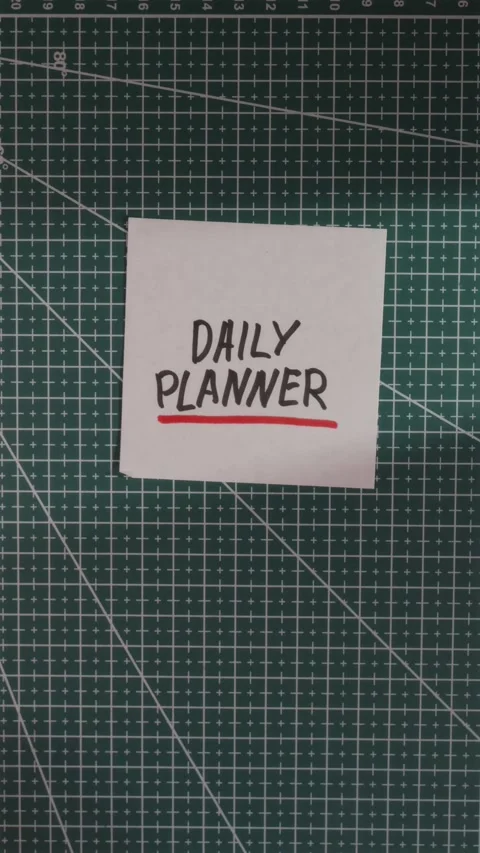 Hand placing Daily Planner paper note on green cutting mat Stock Footage 341246071