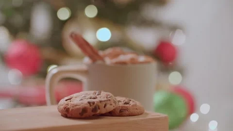Hand placing down chocolate chip cookies next to warm holiday christmas drink 库存影片 220755759