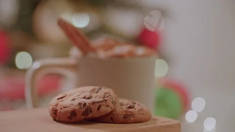 Hand placing down chocolate chip cookies next to warm holiday christmas drink 库存影片 220755764