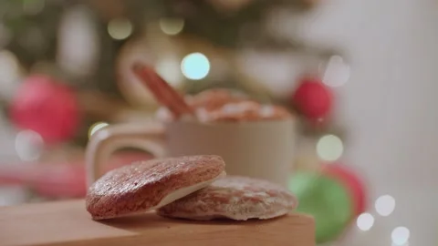 Hand placing down gingerbread cookies next to warm holiday christmas drink 库存影片 220755758