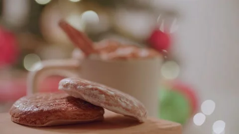 Hand placing down gingerbread cookies next to warm holiday christmas drink 库存影片 220755767