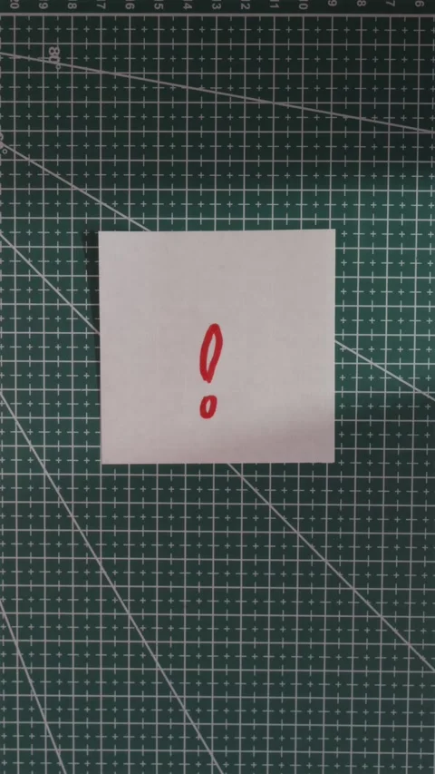 Hand placing exclamation mark paper note on green cutting mat Stock Footage 341246082