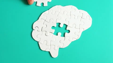 Hand Placing Final Puzzle Piece into Brain Shape on Teal Surface Video stock 295112158