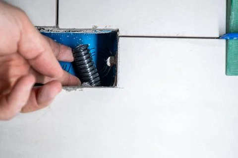 Hand placing flexible electrical conduit inside a blue electrical box openi.. Stock Photos