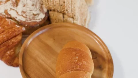 Hand Placing Fresh Bread Rolls on a Wooden Plate Stock Footage 339401598