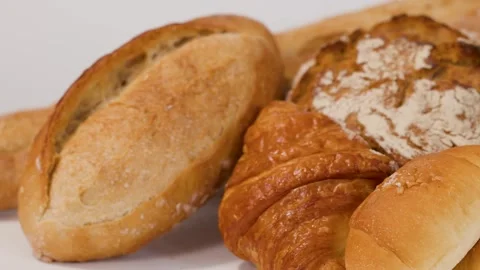 Hand Placing Fresh Crusty Bread Loaf with Assorted Bakery Pastries Stock Footage 337227044