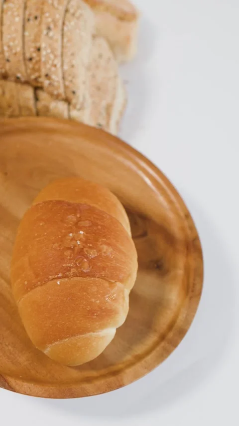 Hand Placing Fresh Golden Bread Rolls on a Wooden Plate Stock Footage 338321416