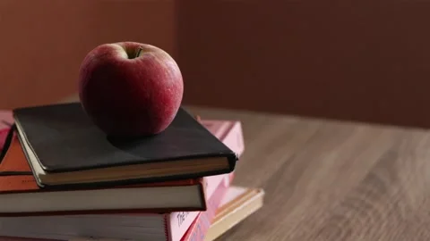Hand placing fresh green apple on stack of school textbooks Stock Footage 340139176