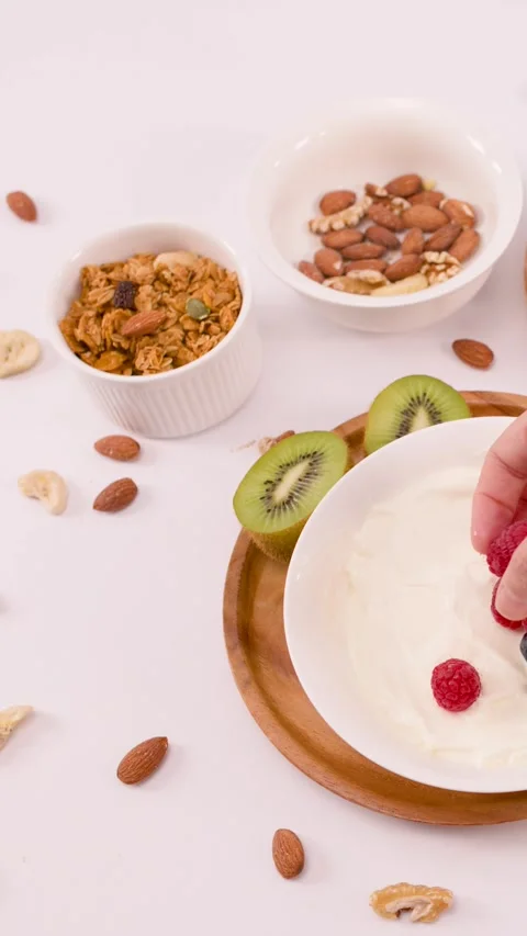 Hand Placing Fresh Raspberries and Blueberries into Greek Yogurt Bowl Stock Footage 337917905