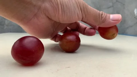Hand Placing Fresh Red Grapes on a Table Stock Footage 341303222