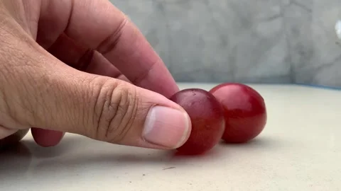 Hand Placing Fresh Red Grapes on Table Stock Footage 341303415