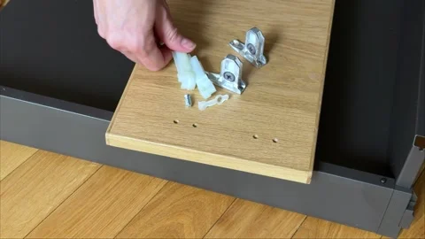Hand placing furniture hardware elements on wooden drawer front panel close up Stock Footage 333788863
