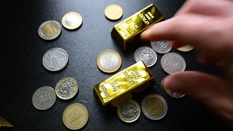 Hand placing gold bars among coins representing financial growth and wealth Stock Footage 331120722