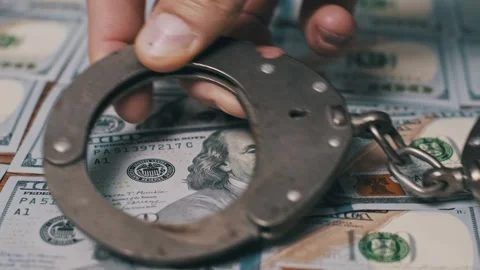 Hand Placing Handcuffs On US Dollar Bills Stock Footage 320587107