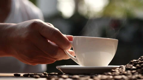 Hand placing hot coffee cup with coffee beans and natural steam smoke Stock Footage 148026699