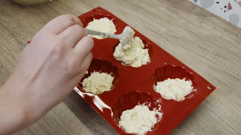 A hand placing ingredients into a muffin pan. Stock Footage 266425451