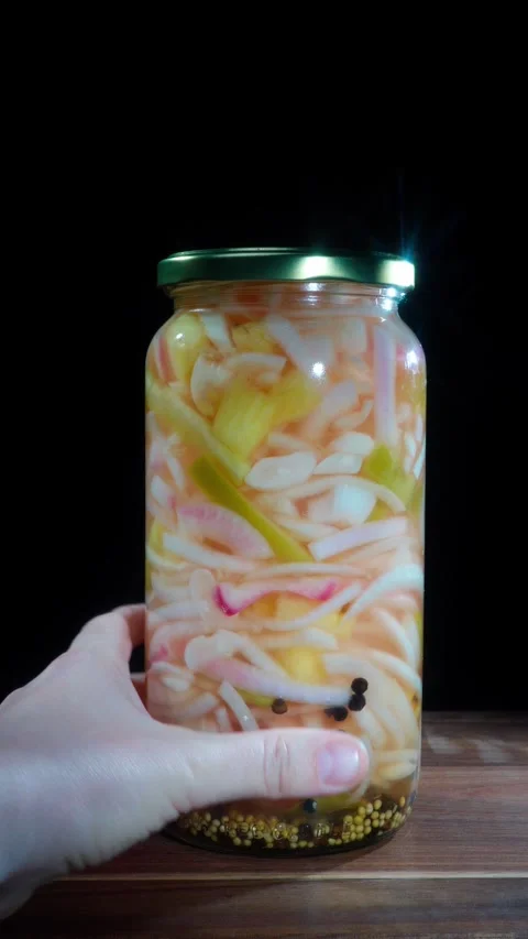 Hand Placing Jar Of Pickled Pineapple And Onions On Wooden Table Stock Footage 324769709