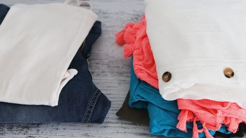 Hand placing Keep and Discard text on top of fashion clothes folded and stack Stock Footage 116714615