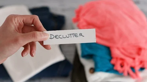 Hand placing Keep and Discard text on top of fashion clothes folded and stack Stock Footage 116714775