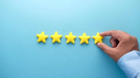 Hand placing last yellow star on blue background, completing a five-star ra.. Stock Footage 332625368
