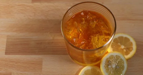 Hand placing lemon in iced cocktail then stirring beverage Stock Footage 125785016