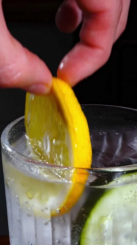 Hand Placing Lemon Slice in Cocktail Glass with Ice Macro Stock Footage 324599069