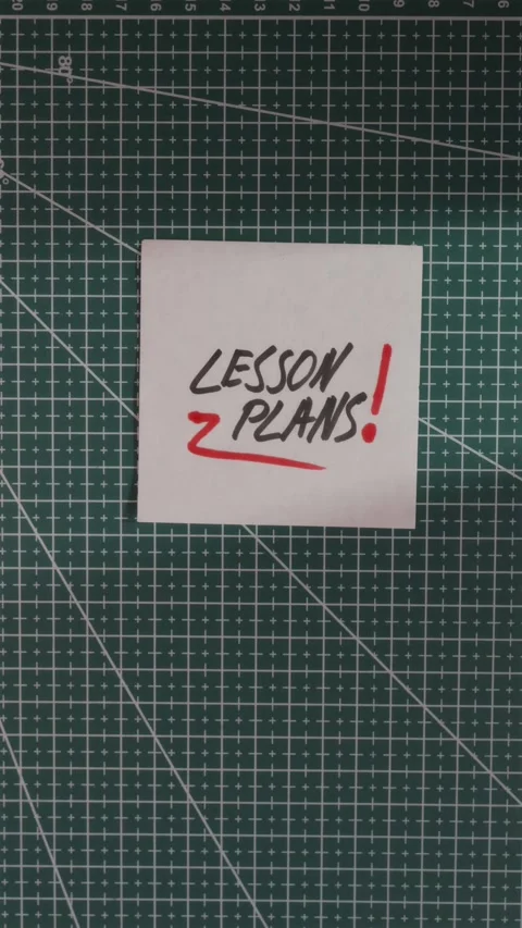 Hand placing Lesson Plans paper note on green cutting mat Stock Footage 341246125