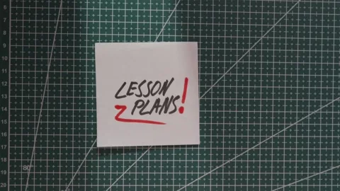 Hand placing Lesson Plans paper note on teacher workspace Stock Footage 341269347