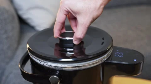 Hand placing lid on modern smart glass kettle Stock Footage 336643817