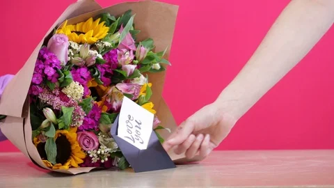 Hand placing a love note by a well arranged floral composition Stock-Footage 124664120