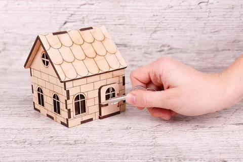 Hand placing mailbox in front of small wooden house model Stock Photos