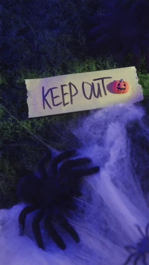 Hand placing mini pumpkin near Keep Out sign in blue light Stockbeeldmateriaal 342423193