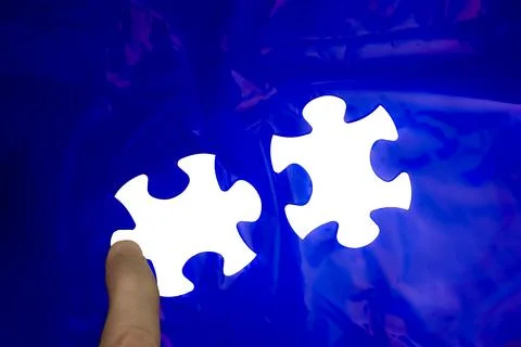 Hand placing a missing puzzle piece with a blue background Stock Photos