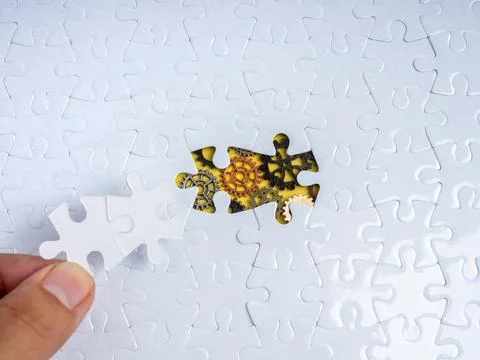 Hand placing missing puzzle piece into system with visible gears symbolizin.. 스톡 사진