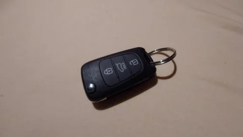 Hand placing a modern car remote key fob on a plain surface Vídeos de archivo 333641510