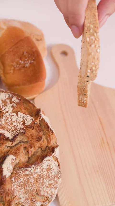 Hand Placing Multigrain Bread Slice on Wooden Cutting Board Stock Footage 337768779